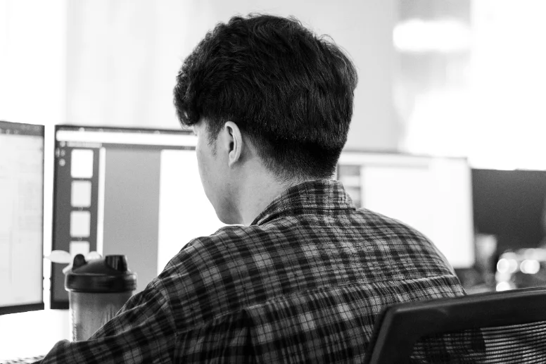A developer at a desk in front of two monitors of source code.