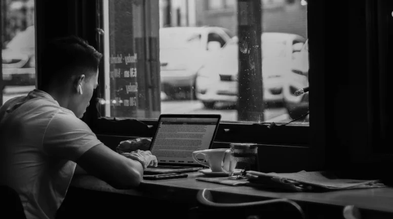 Someone working on a laptop at a café window.
